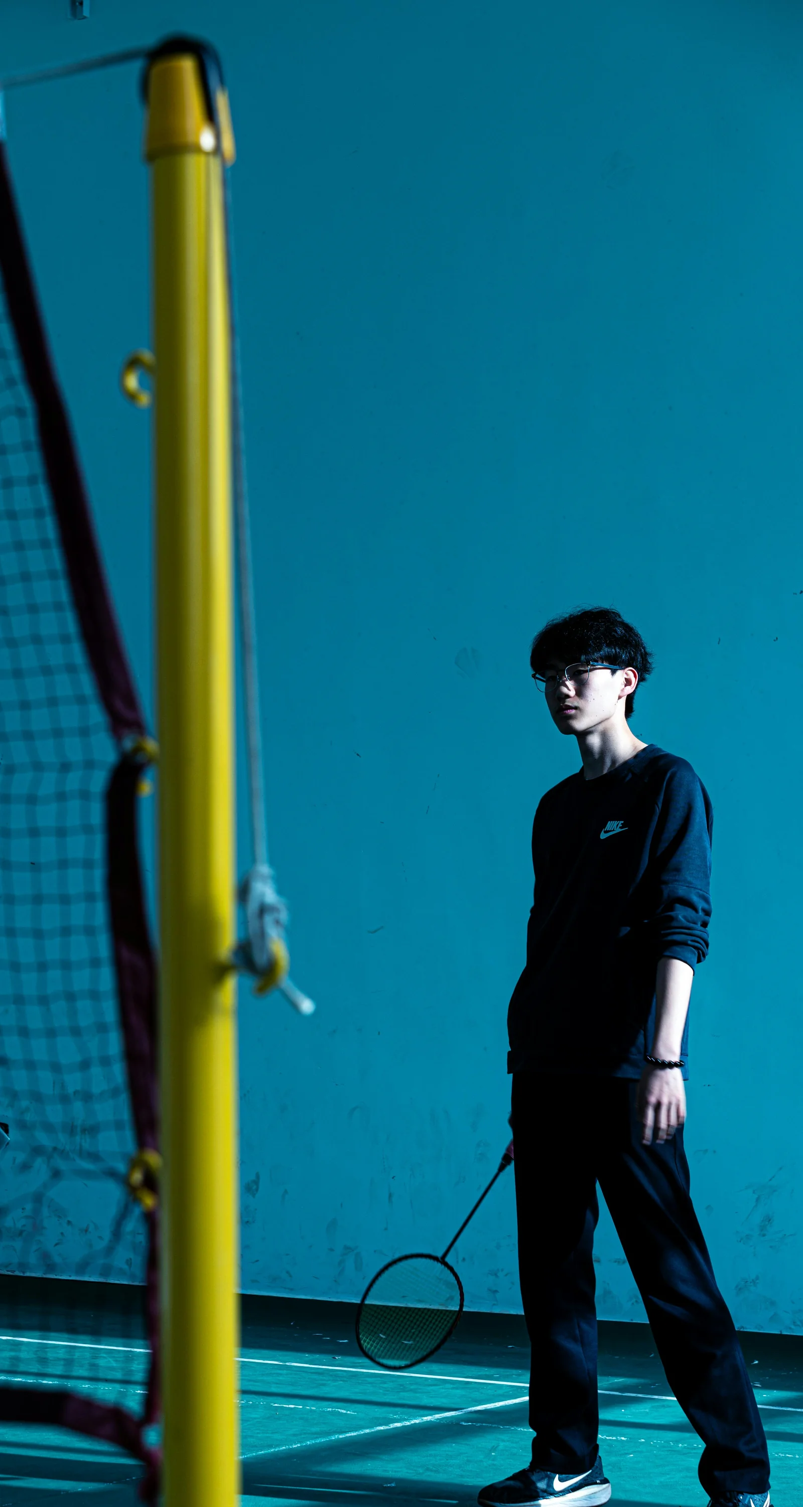Badminton player standing near net on indoor court in competitive setting