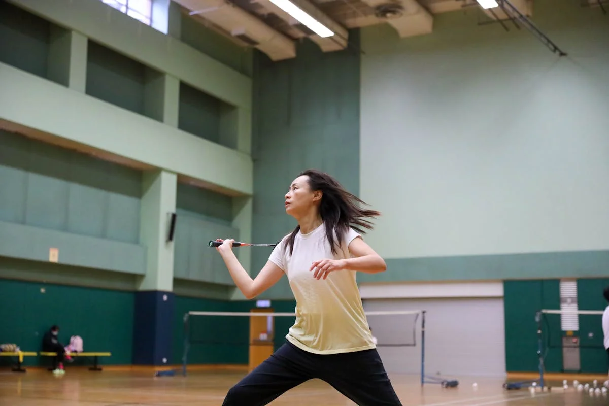 Badminton player in action mid-swing on indoor court during BWF World Tour match