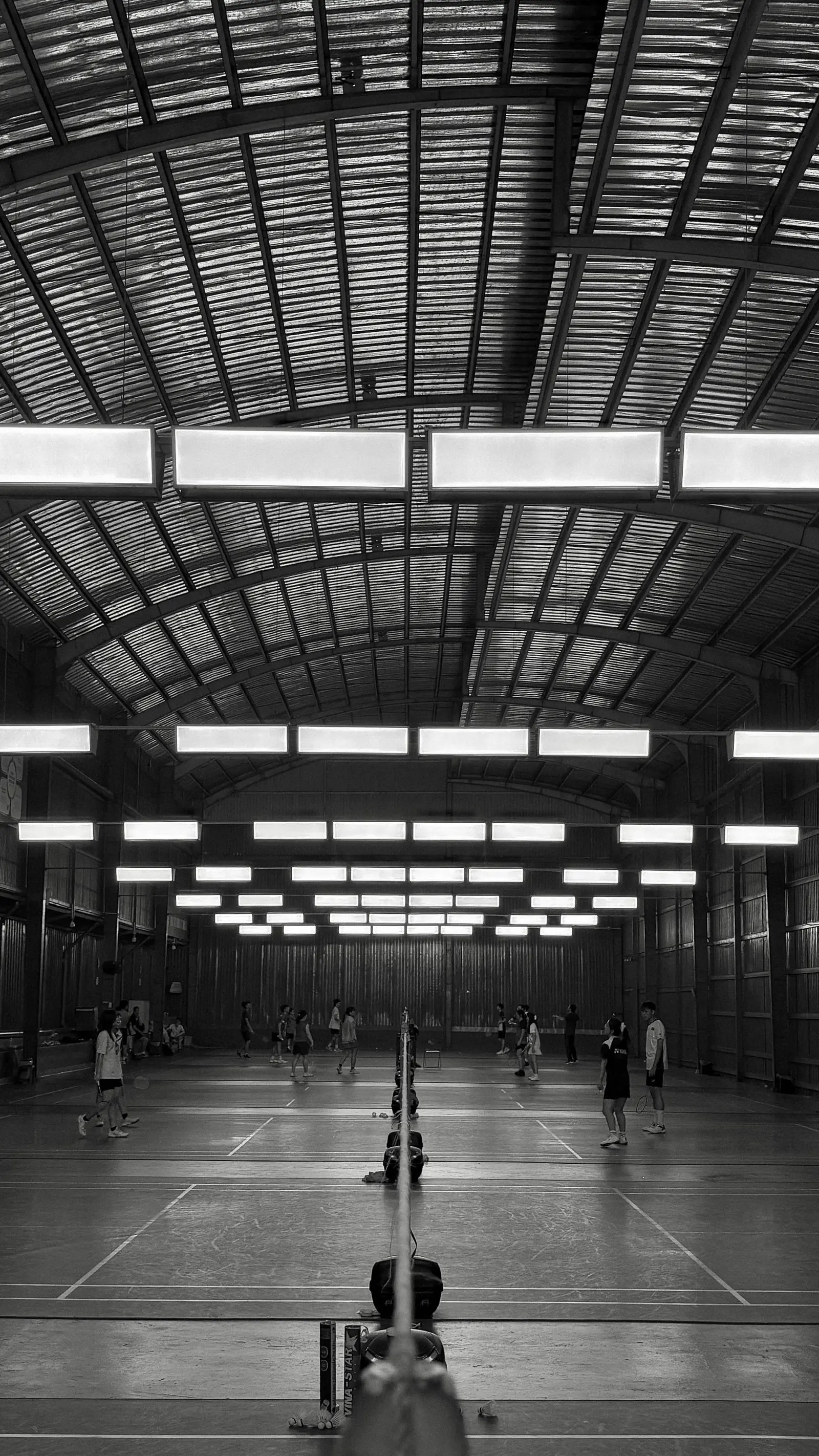 Badminton court with multiple players showing different performance levels by round stage