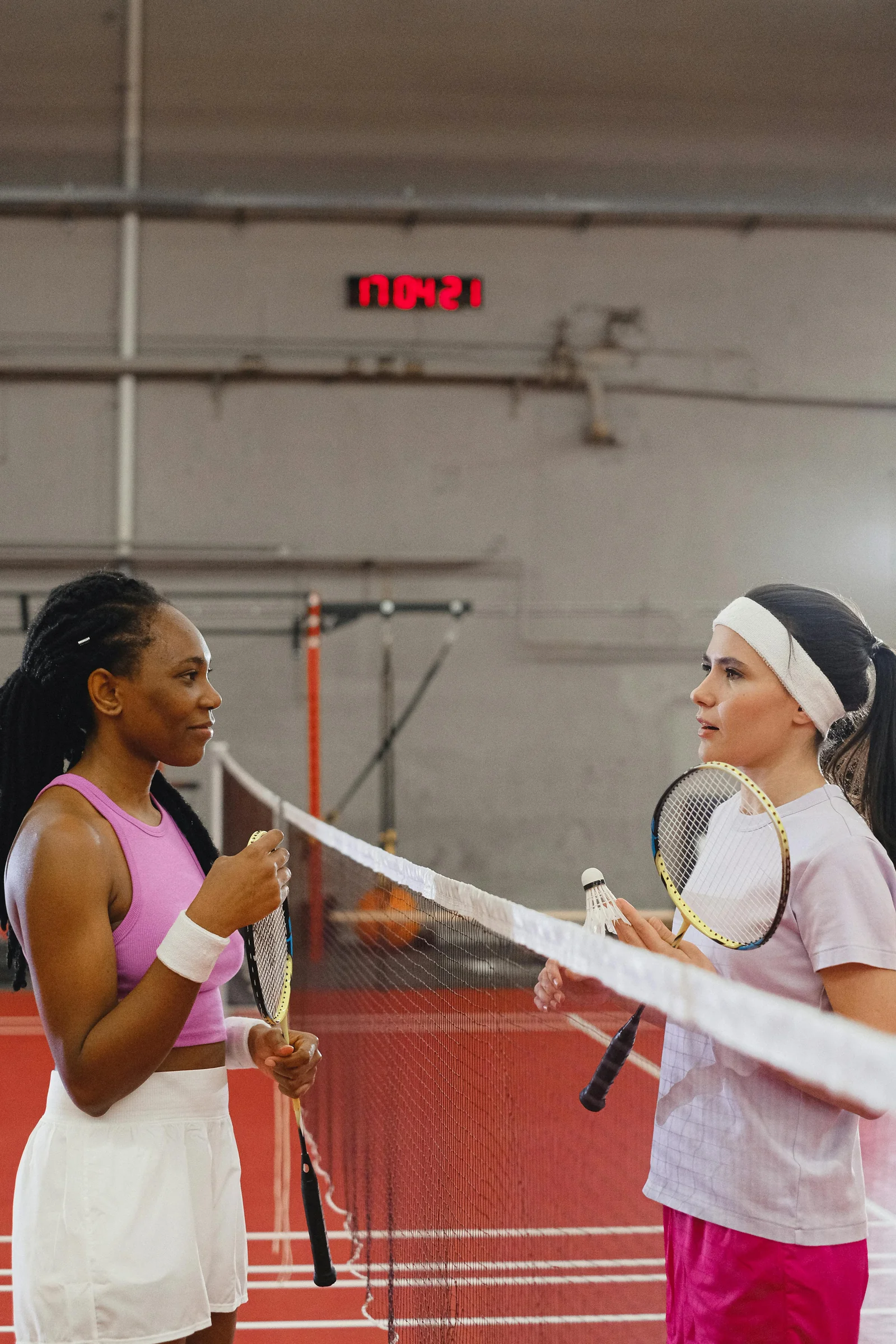 Two badminton players facing each other at the net before a match